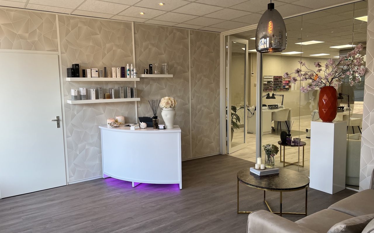 De salon van Sounds of Beauty: witte ontvangstbalie, schappen met producten en de lakwand