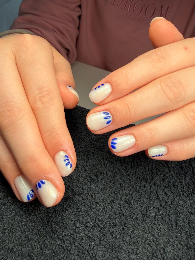 Witte nagels met blauwe bloemtekening