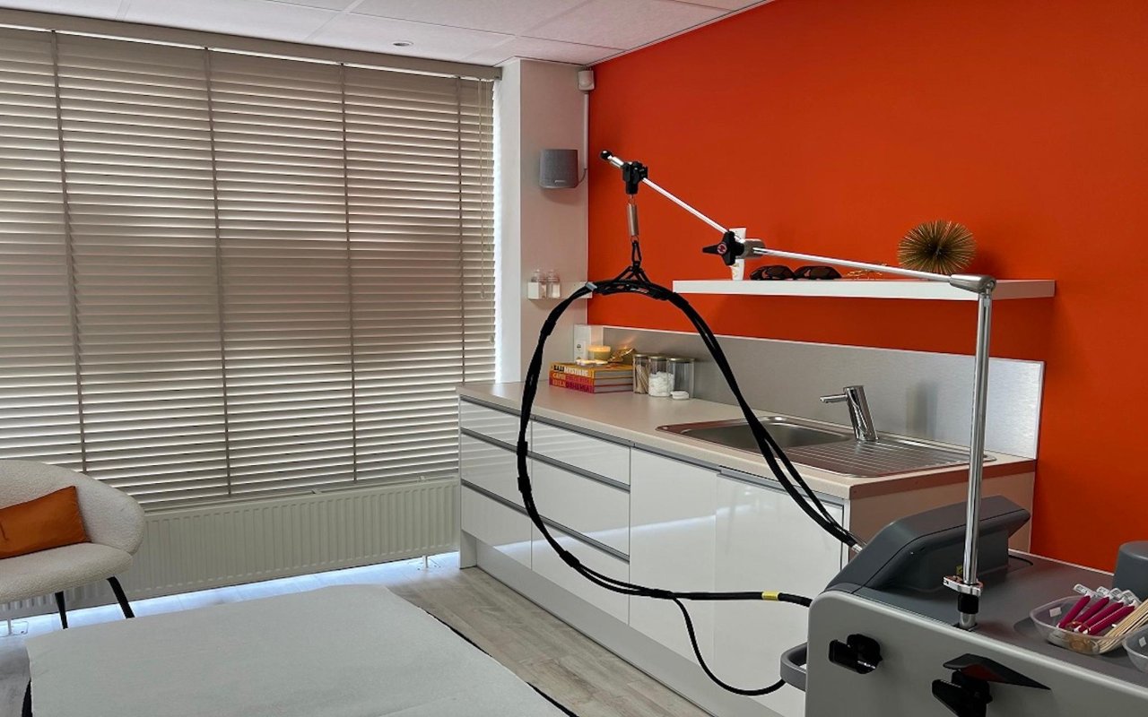 De laserkamer van Sounds of Beauty met oranje muur en behandelstoel